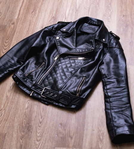 Black leather jacket on a wooden background close up
