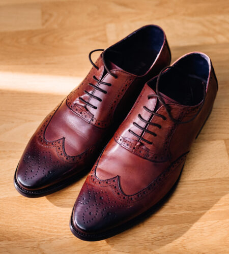 Red leather shoes stand on the light wooden floor