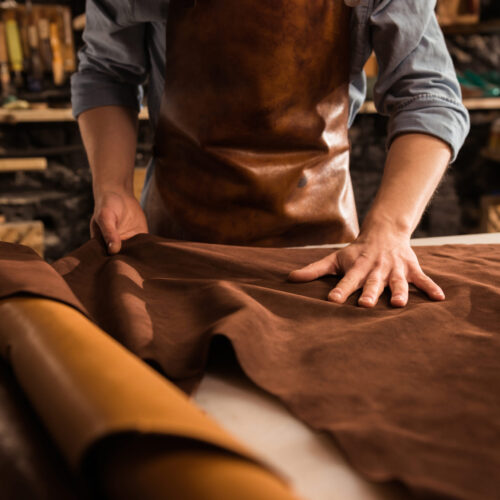 Close up of a cobbler working with leather textile Close up of a cobbler working with leather textile at his workshop